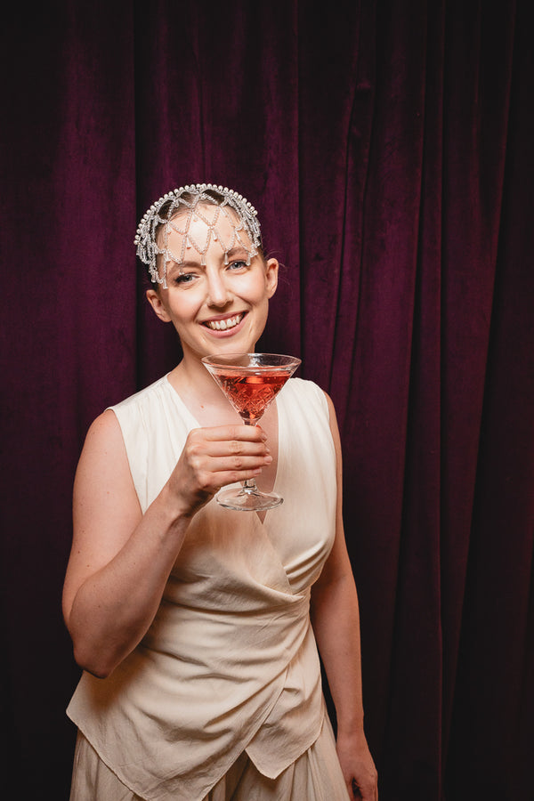 Lächelnde Braut mit Brauthaarreif KONA und Cocktailglas im Roaring-Twenties-Look