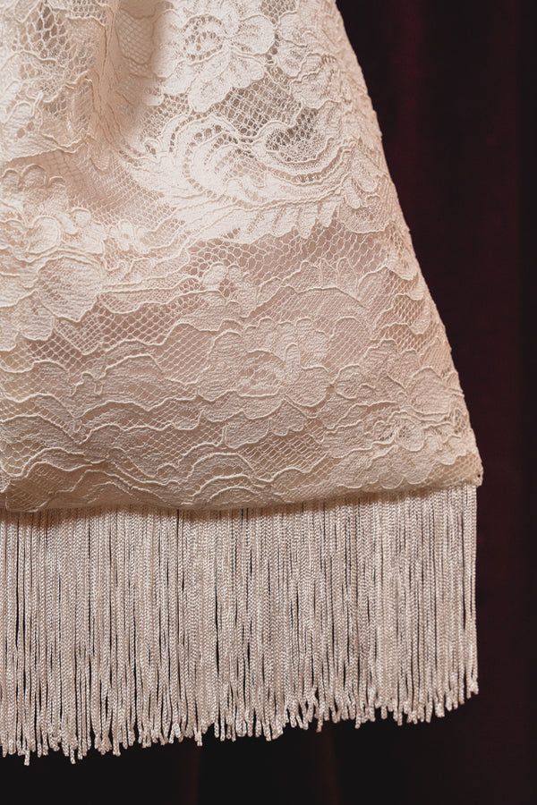 Detailaufnahme des Spitzenmusters und Fransensaums der Brauttasche ALOHI von MOANA